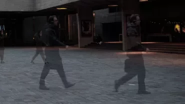 Blurred motion of people walking outside a theatre at night.