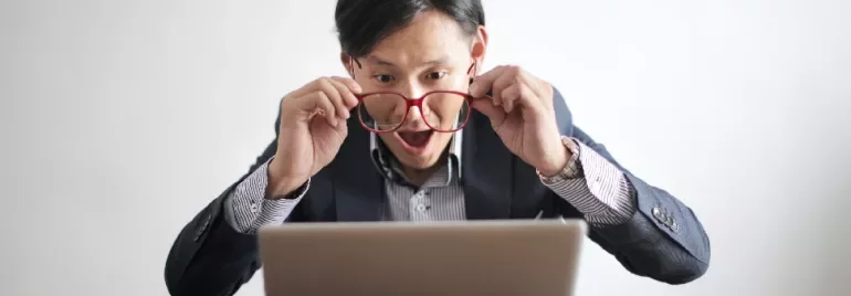 Excited man looking at laptop screen with surprise.